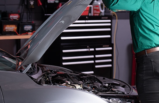 Front of a Honda civic and man opening the hood