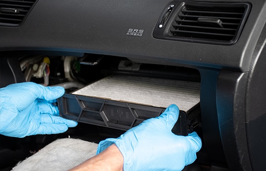 Mechanic holding cabin air filter housing tray with two hands