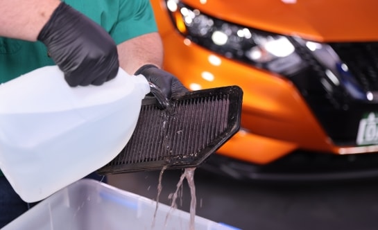 Auto parts professional rinsing an engine air filter with water