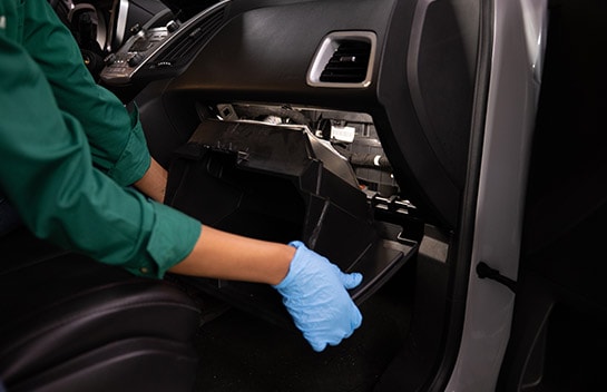 Anna lowers and removes the glove box from the Equinox to access the cabin air filter assembly behind it.