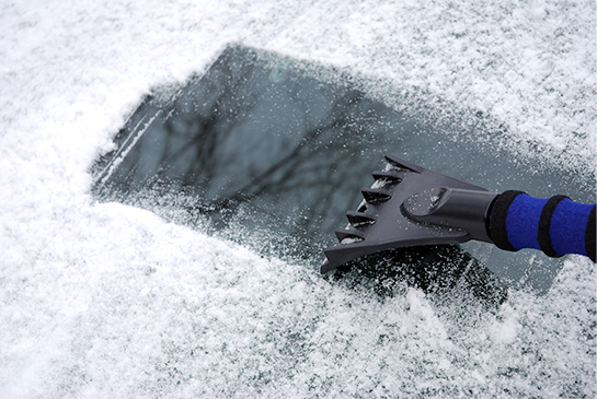 An ice scraper removing a thin layer of ice from a windshield.