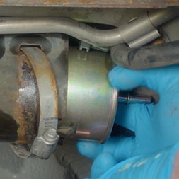 hand removing fuel filter from car
