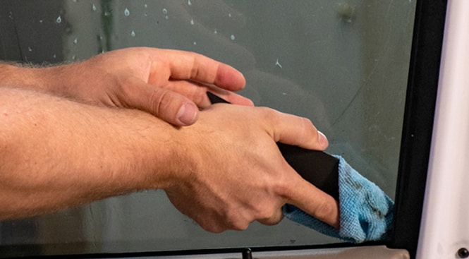 Drying the interior window with a squeegee and cloth.
