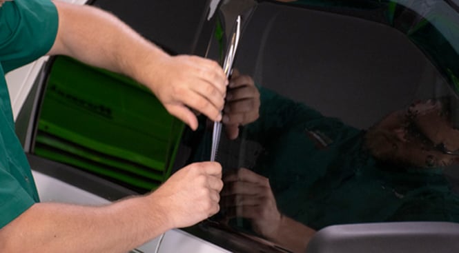 Using a squeegee and gently pressing down the film to temporarily hold it in place for trimming.