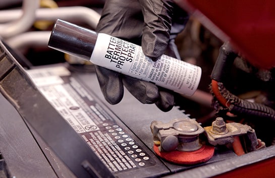 Our expert holds a small spray can of battery terminal protective spray.