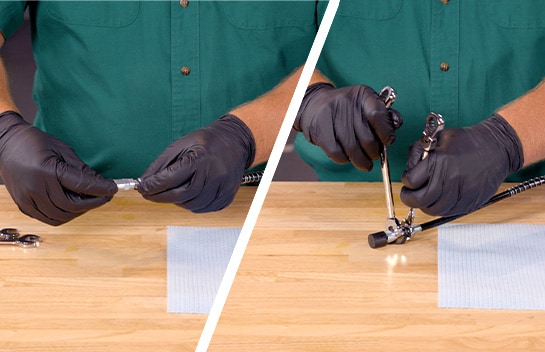 A coupler is attached to the grease gun hose and tightened with wrenches.