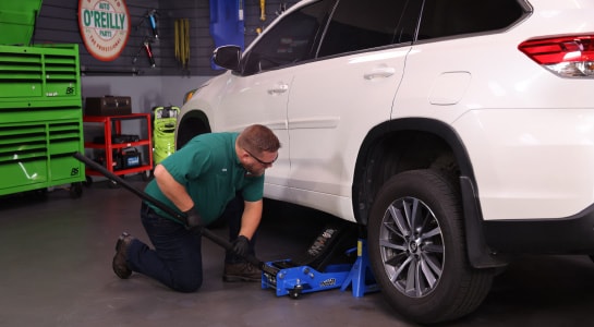 Our expert uses a floor jack to lift the front end of the Highlander.
