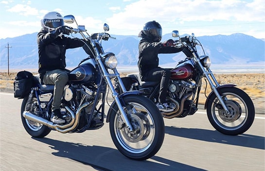 Two riders driving motorcycles on an open highway