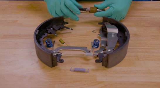 Install new hardware, including the return spring, onto the rear brake shoe.