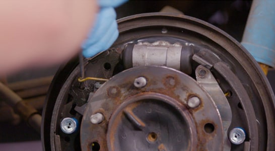 Use your spring tool or screwdriver and needle-nose pliers to install the upper return spring.