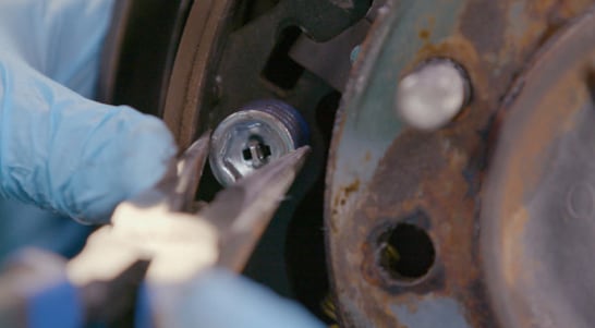 Remove the brake shoe hold-down spring cup with needle-nose pliers.