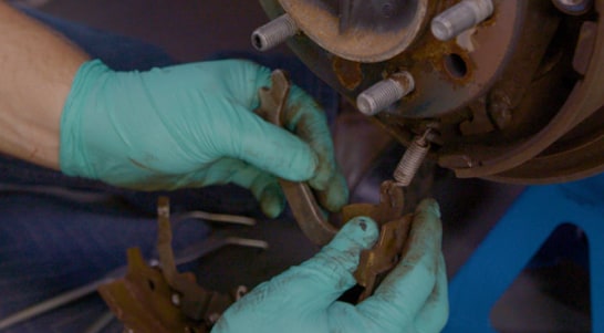 Detach the automatic brake adjust lever spring and adjustment lever from the front brake shoe.