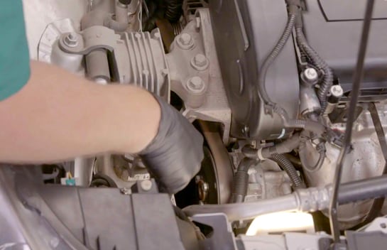 Use a 13mm socket and ratchet or breaker bar to rotate the tensioner and slip the belt off the pulley.