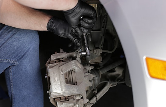 Use a 10mm socket and ratchet or breaker bar to loosen and remove the caliper bolts.