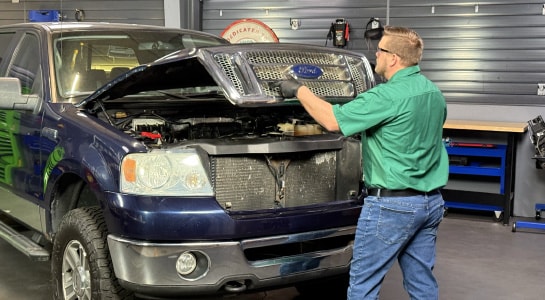 Auto parts professional opening a Ford F-150 hood before installing a new battery