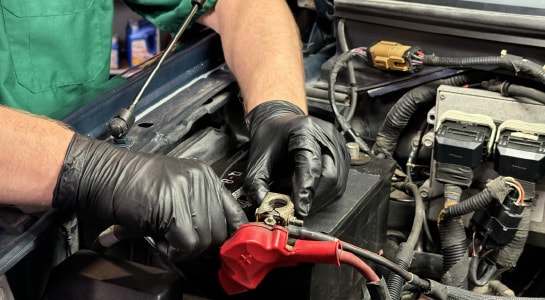 Auto parts professional removing a red positive terminal cover