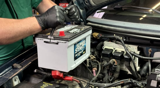 Auto parts professional removing a Ford-150 battery from the engine bay