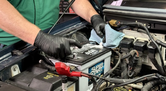 Auto parts professional applying battery terminal cleaner with a shop towel