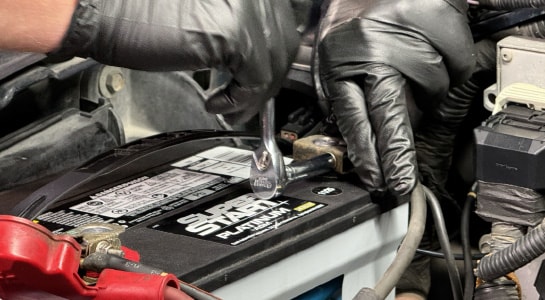 Auto Parts Professional securing a hold-down bracket and reconnecting cables