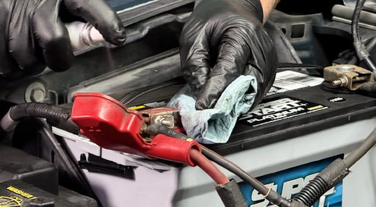 Auto parts professional applying terminal protector spray to battery components