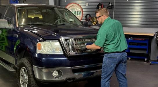 Auto parts professional closing a Ford F-150 hood after installing a new battery