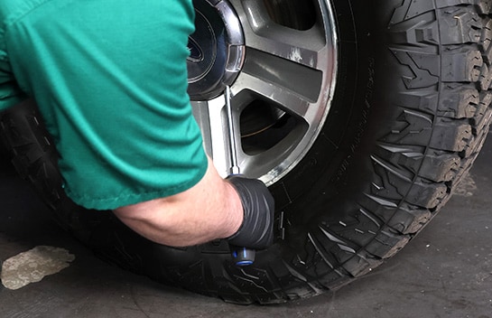 Auto parts professional removing a hub cap on a Ford F-150