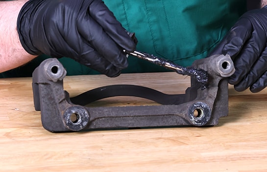Auto parts professional installing new hardware on a Ford F-150 caliper bracket