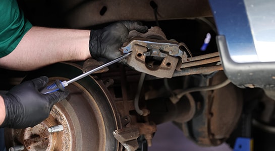 Auto parts professional removing old brake pads on a Ford-F-150