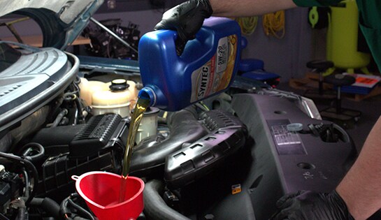 Auto parts professional adding 7 quarts of motor oil to a Ford F-150 
