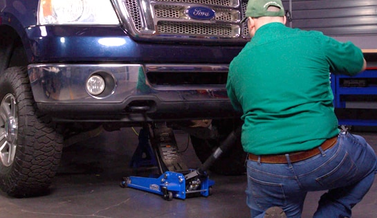 Auto parts professional lowering a Ford F-150 from jack stands